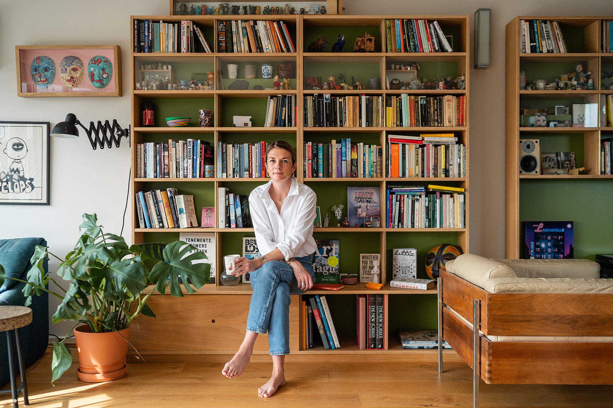 Eliza Fricker photographed at home sat in informally front of a bookcase.